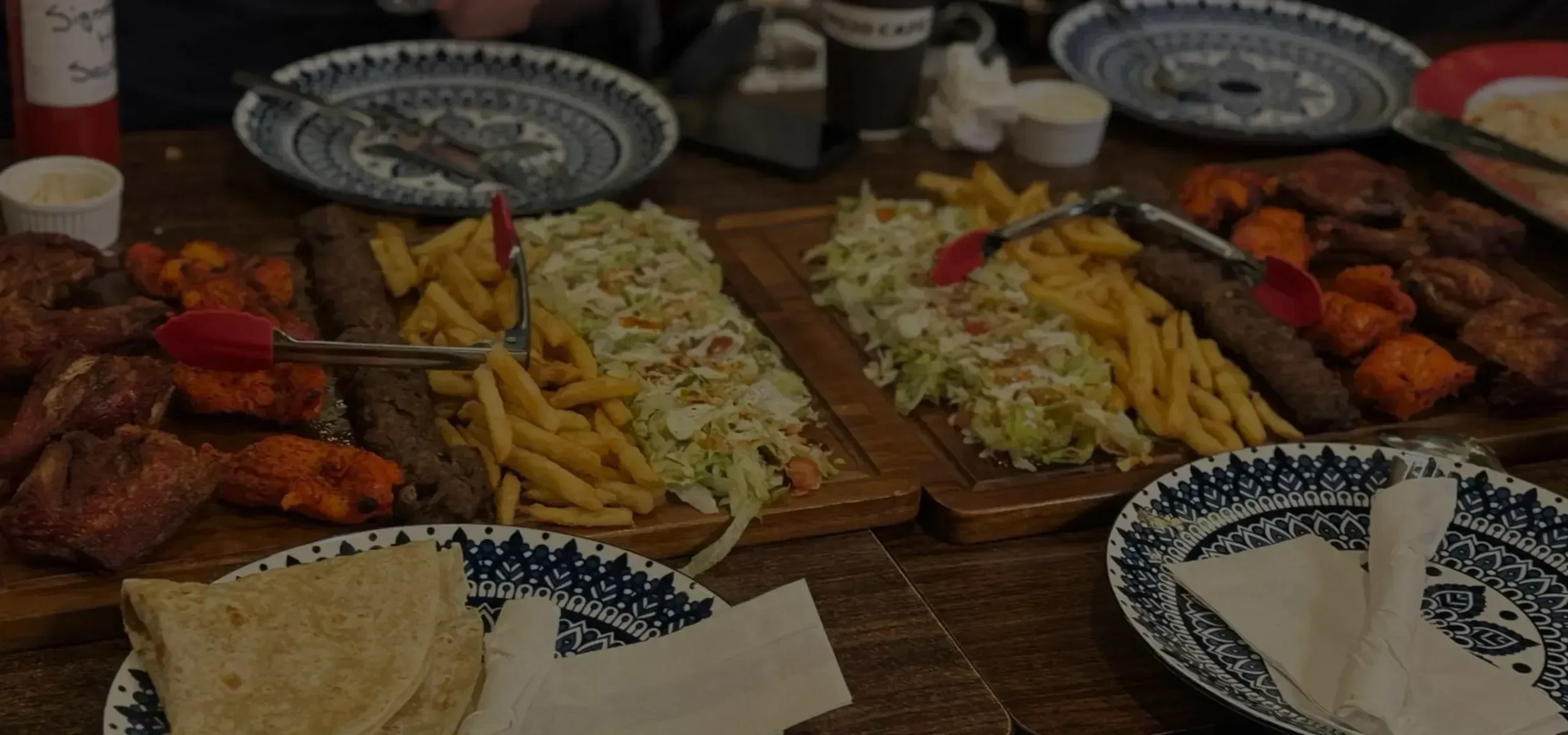 Afghani food platter with kebabs, fries, salad, and bread.